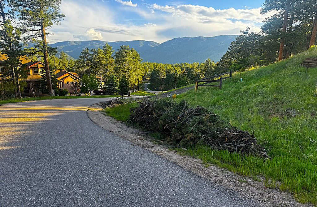 Piles of tree branches and brush await pickup along a roadside in Perry Park as part of the District's slash pile program, which helps residents reduce wildfire fuel around their homes.